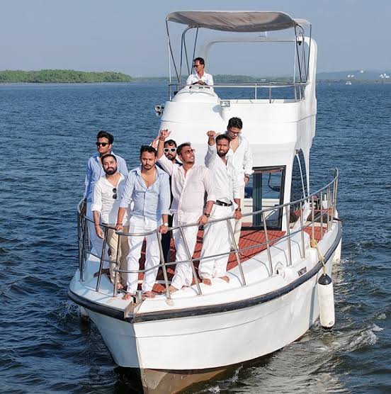 Group dressed in white on a two-level yacht in Goa