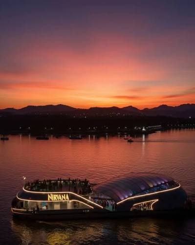 Cruise boat with an illuminated canopy sailing the Mandovi river in the evening afterglow