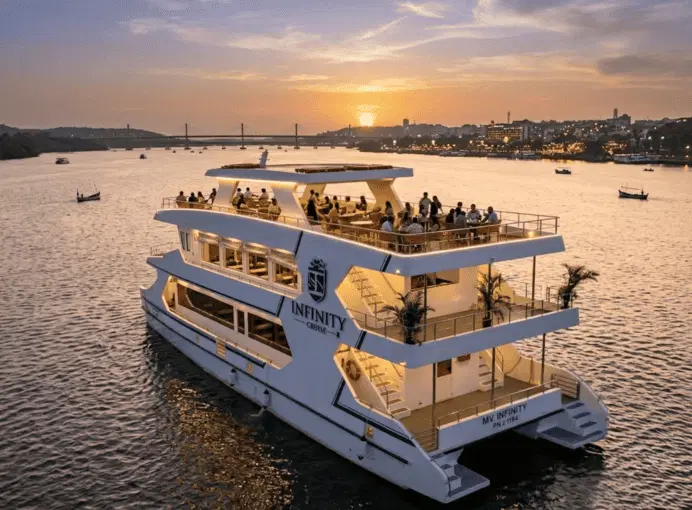 Sunset cruise boat sailing the Mandovi river with the sun going down over the horizon and a bridge in the background